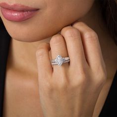 a close up of a person wearing a ring with a pear shaped diamond on it