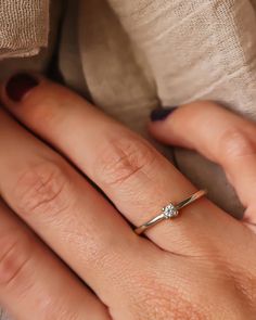 a woman's hand with a diamond ring on her left finger and the other hand holding an engagement ring