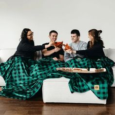 three people sitting on a couch eating pizza