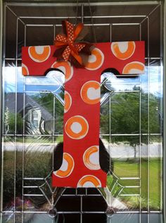 a cross made out of red and orange paper with a bow hanging from it's side