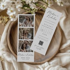 save the date cards on top of a wooden plate with white flowers in the background