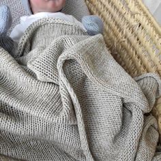 a baby wrapped up in a blanket on top of a wicker basket next to a wall