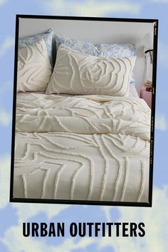 an advertisement for the urban outfitters featuring a bed with white comforter and blue pillows