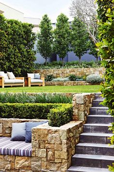 an outdoor seating area with stone walls and steps leading up to the grass covered lawn