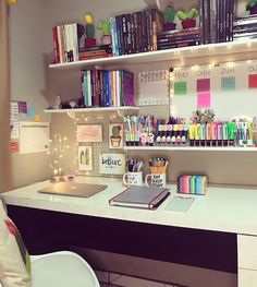 a desk with a laptop and many books on it, along with other office supplies