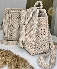 two crocheted handbags sitting on top of a table next to a feather