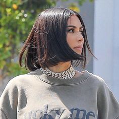 a woman with black hair wearing a grey sweatshirt and silver choker on her neck