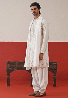 Elevate your style with White Embroidered mirror Kurta. Crafted from georgette, the classic white kurta features intricate hand embroidery and real mirror work, adding a touch of sophistication. Completed with a same-color embroidered dupatta and matching pants. Perfect for Sangeet, Mehendi, Haldi, or as a wedding guest outfit. Composition : Kurta, Patiyala & Dupatta : Viscose Georgette Care: Dry Clean Only and Vacuum Storage This product can be customized for sleeves, length and colour Delivery Designer Cotton Silk Sherwani With Mirror Work, Unstitched Off White Kurta With Mirror Work, White Embroidered Cotton Silk Bandhgala, Wedding Cotton Sherwani With Mirror Work, Embroidered White Cotton Silk Bandhgala, Fitted White Cotton Silk Kurta, White Fitted Cotton Silk Kurta, Traditional Cotton Silk Kurta With Mirror Work, Off White Mirror Work Kurta For Eid