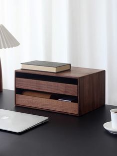 a laptop computer sitting on top of a desk next to a wooden box with drawers