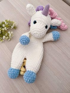 a crocheted stuffed animal laying on top of a wooden table next to flowers