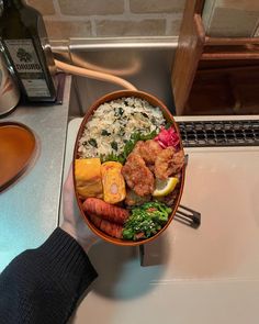 a bowl filled with rice, meat and veggies next to a bottle of wine