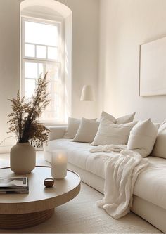 a living room filled with white furniture and a round coffee table in front of a window