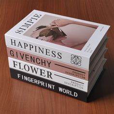 three books stacked on top of each other in front of a wooden table with the words happiness, givechy flower and fingerprint world