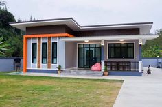 a small house with an orange and white front door on the grass in front of it