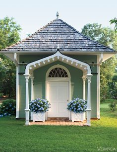 an image of a small house with potted plants on the front and side porch