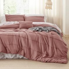 a bed covered in pink sheets and pillows