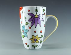 a white coffee cup with colorful flowers painted on the outside and inside, sitting on a gray surface