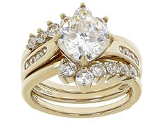 3.25ct cushion cut Lab Created Strontium Titanate solitaire with 1.28ctw round white zircon 18k yellow gold over sterling silver ring with guard. Measures approximately 0.63"L 0.25"W. Not sizable. Accent stones primarily zircon. Solitaire Cushion Cut Cubic Zirconia Jewelry, Cushion Cut Solitaire Cubic Zirconia Jewelry, Gold Cubic Zirconia Bridal Sets With Center Stone, Gold Bridal Sets With Center Stone Cubic Zirconia, Gold Bridal Set With Round Cut Center Stone, Classic Gold Bridal Sets With Diamond Accents, Classic Yellow Gold Cubic Zirconia Bridal Sets, Classic Yellow Gold Bridal Sets With Cubic Zirconia, Classic Gold Bridal Sets With Center Stone