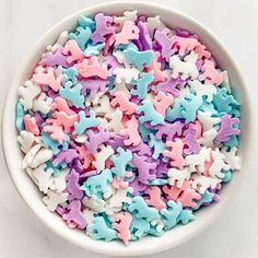 a white bowl filled with pink, blue and purple stars