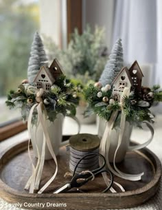 two small christmas trees are sitting on a tray next to some twine spools