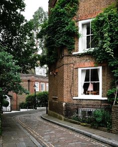 a brick building with ivy growing on it's side and a cobblestone street in front