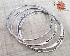 "This personalized name bangle is made of sterling silver (92.5%) and is engraved with the name and birthdate of your loved one. Choose the number of bangles you want included in your set. Each bangle can have either one flattened area or two flattened areas on opposite sides of the bangle. Each flattened area can be engraved with text (up to 16 characters, counting spaces and punctuation). Text is only engraved on one side of each flattened area. Most people choose to have a name and a date acr Engraved Bangle For Mother's Day Personalized Gift, Engraved Bangle For Personalized Mother's Day Gift, Silver Sterling Silver Name Bracelet For Promise, Mother's Day Engraved Bangle For Personalized Gift, Sterling Silver Engraved Bangle For Anniversary, Engraved Name Bangle Bracelet For Mother's Day, Mother's Day Engraved Name Bangle Bracelet, Personalized Round Bracelet For Promise, Personalized Round Bracelets For Promise