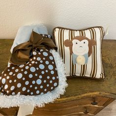 two pillows and a stuffed animal on a wooden bench next to a pillow that has a monkey on it