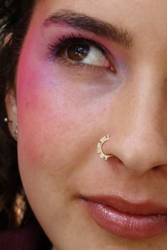 a close up of a person with a nose ring and piercing on their nose,