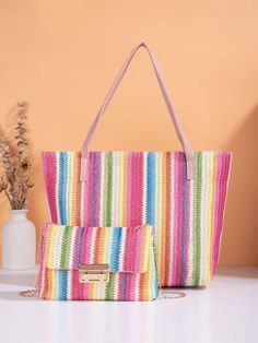 a multicolored bag and purse sitting on top of a white table next to a vase