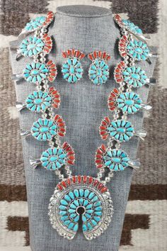 This Sleeping Beauty turquoise, coral and sterling silver squash blossom, concho belt, earrings, pin/ pendant, bracelets, and rings set was made by Navajo silversmith Justina Wilson. The back is signed JW and stamped sterling.Squash BlossomLength: 26 1/2"Naja Height: 3"Naja Width: 3"Blossom Length: 1 1/8"Blossom Width: 2 1/8" Concho Belt Belt Length: up to 60" Belt Buckle Length: 3 1/4" Belt Buckle Width: 2 1/8" Concho Length: 2 1/2" Concho Width: 1 3/4" EarringsLength: 1 1/2"Width: 1 1/8"Pin/ P Traditional Turquoise Concho Jewelry, Traditional Turquoise Jewelry With Concho, Blue Western Style Jewelry With Inlay, Western Style Concho Jewelry Collectible, Blue Southwestern Jewelry With Concho, Southwestern Blue Concho Jewelry, Southwestern Style Blue Concho Jewelry, Traditional Blue Concho Jewelry, Silver Squash Blossom Necklace