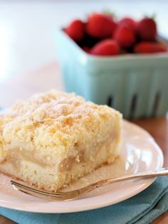 a piece of cake sitting on top of a white plate next to a bowl of strawberries