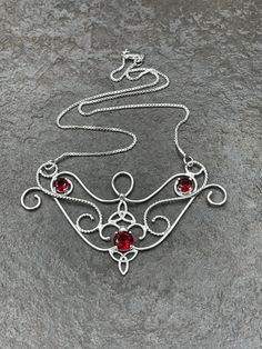 I love Victorian themed jewelry with an Edwardian, Elvish-inspired flair, and I hope I've captured it within this piece! I shall custom create this gorgeous Renaissance style necklace, in sterling silver, with three faceted gemstones of your choosing in the drop-down menu. I've shown garnet here in the images displayed. The center gemstone is 8mm round and the two sides are 4mm round. The chain will be soldered to each side and I will use a 1.2mm thick sterling box chain. I think this piece look Red Artistic Design Jewelry For Gift, Handmade Fantasy Round Pendant Jewelry, Fantasy Style Handmade Round Pendant Jewelry, Hand Forged Fantasy Jewelry As A Gift, Fantasy Style Hand Forged Jewelry As Gift, Hand Forged Red Jewelry As A Gift, Hand Forged Red Jewelry For Gifts, Artisan Red Jewelry With Artistic Design, Handmade Sterling Silver Fantasy Necklace