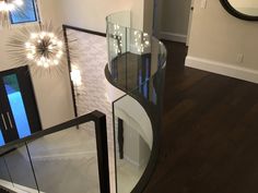 a curved glass table in the middle of a room with wooden floors and white walls