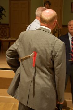 two men in suits standing next to each other and one is wearing a red tie