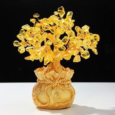 a golden vase filled with lots of yellow glass flowers on top of a white table