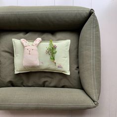 a green chair with a bunny pillow on it's back and flowers in the middle