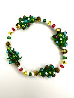 Rock around the Christmas tree with this glass beaded stretch bracelet. Glass seed beads add onto the bright colors of the tree making it the merriest accessory this holiday season!  Bracelets are available in a variety of lengths.  Pick your custom length from the drop down menu below.  Please be aware that beading may slightly differ from what is pictured as to accommodate selected sizing.  All our bracelets are made with quality in mind.  With that being said, all bracelets should be treated Christmas Beaded Stretch Bracelet Gift, Festive Christmas Bracelets With Round Beads, Christmas Festive Round Beads Bracelets, Festive Green Beaded Bracelets With Colorful Beads, Adjustable Beaded Bracelets For Holiday Party, Adjustable Beaded Bracelets For Party And Holiday, Festive Green Beaded Bracelets, Adjustable Christmas Beaded Bracelets, Christmas Holiday Bracelets With Round Beads