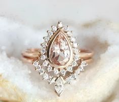 an engagement ring with a pear shaped morganite surrounded by diamonds