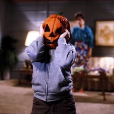 a young boy holding up a jack - o'- lantern in front of his face