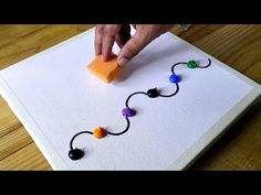 someone is making a string art project with beads and rubber balls on a white board