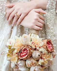 a close up of a person's hand holding a bouquet of flowers and pearls