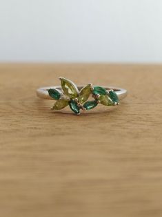 a close up of a ring with leaves on it sitting on a wooden surface,