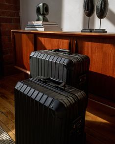 two pieces of luggage sitting on top of a hard wood floor next to a table