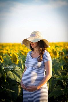 a pregnant woman standing in a field of sunflowers