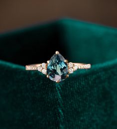 a blue diamond ring sitting on top of a green velvet bag