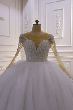 a wedding dress on display in a white room with gold trimmings and sequins