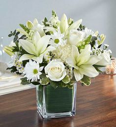 a vase filled with white flowers on top of a wooden table