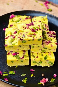 several pieces of yellow fudge on a black plate with pink and green flowers around it