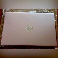 an open laptop computer sitting on top of a plastic bag covered tablecloth with the word hp printed on it