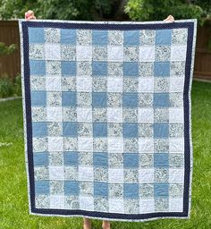 a person holding up a blue and white quilt